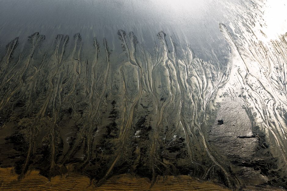 Aerial shot of tidal mudflats showcasing intricate natural patterns at low tide.